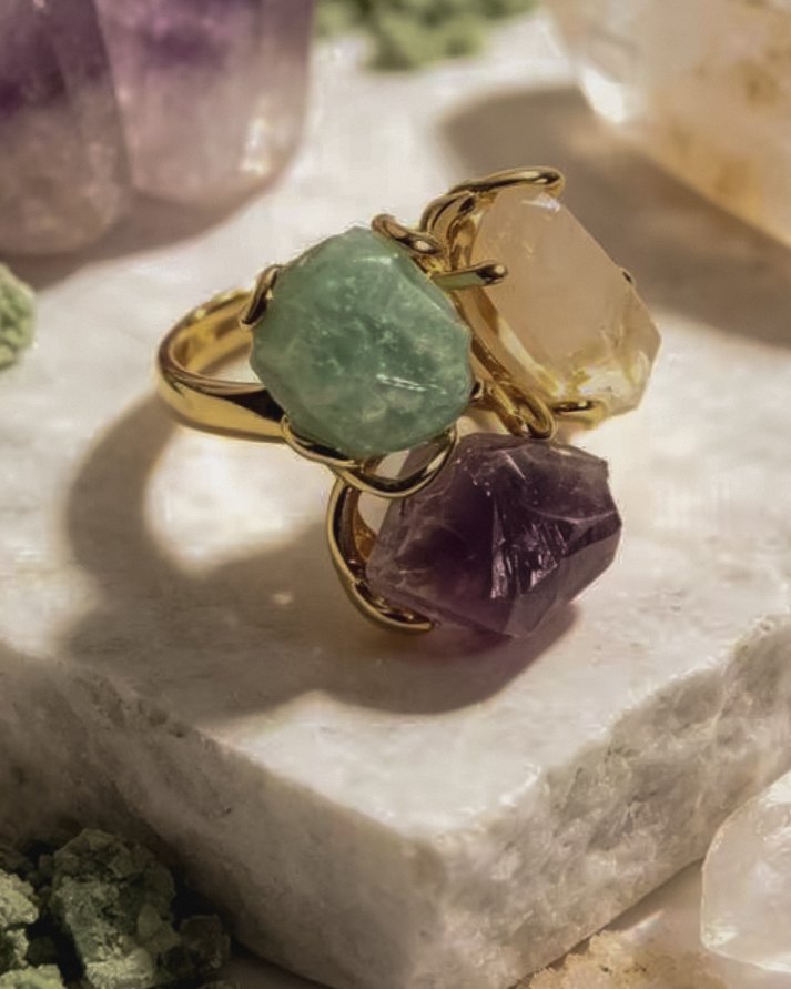 Luna — raw crystal ring with green, pale champagne and deep violet natural stones in a gold-toned setting