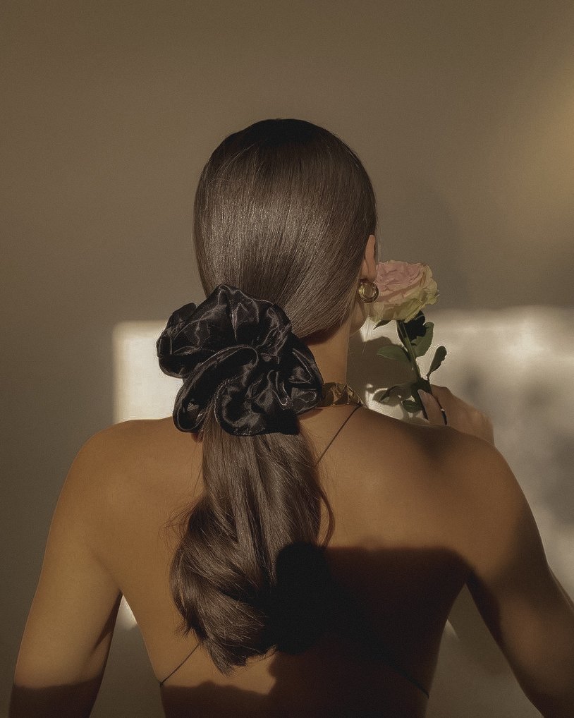 Notte — a generous black silk scrunchie holding a sleek low ponytail