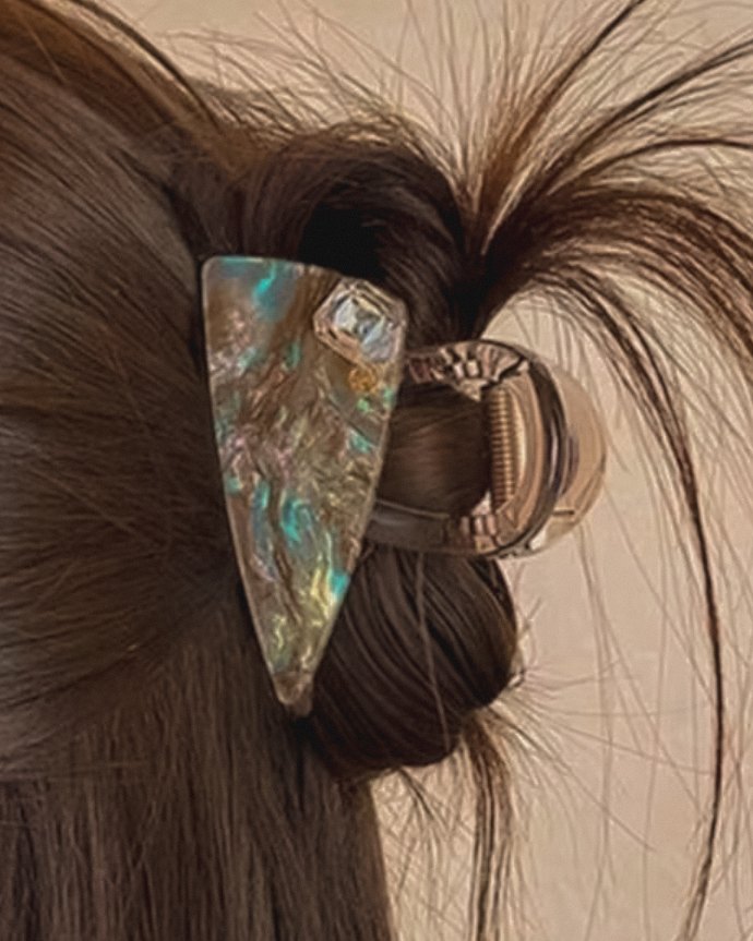 Perla — an iridescent marbled claw clip with a faceted accent, holding a twisted updo